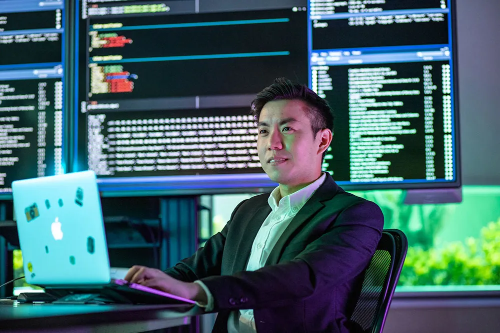 Man in a suit, using a laptop with technology background